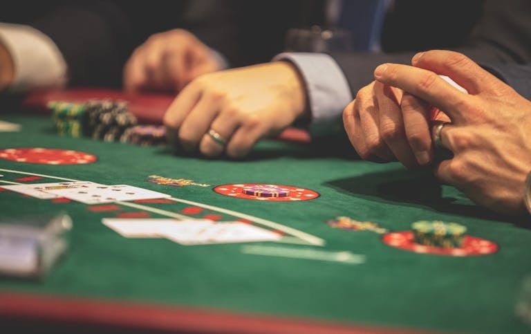 Bets o que é: mãos jogando blackjack em cassino online, com cartas e fichas sobre mesa verde.