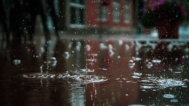 Gotas de chuva intensas formando poça em ambiente urbano, simbolizando o alerta de chuvas e o risco de alagamento no Espírito Santo.